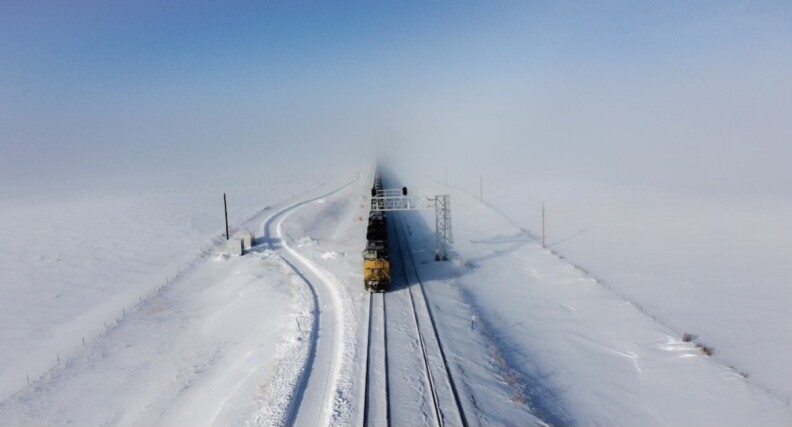 A train on train tracks on a snowy landscape.