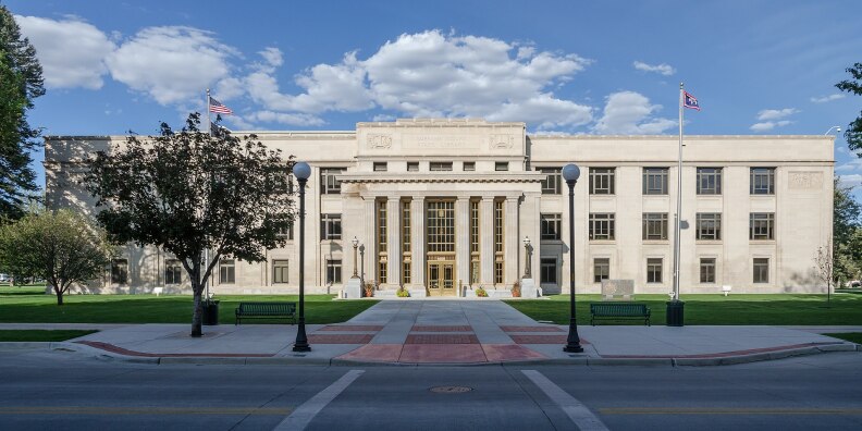 A straight-on shot of a grand three story building, as seen from the street.