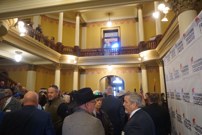 A crowd of people stand in a foyer.