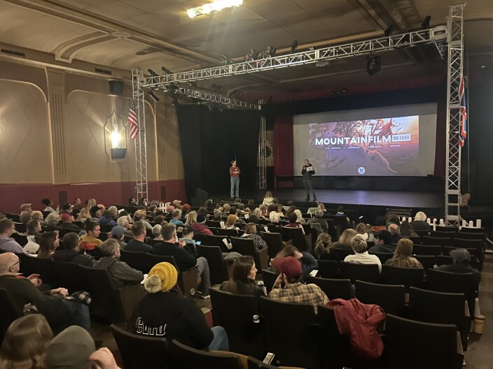 A large group of people in a theater look at the movie screen for Mountainfilm fest in Cody