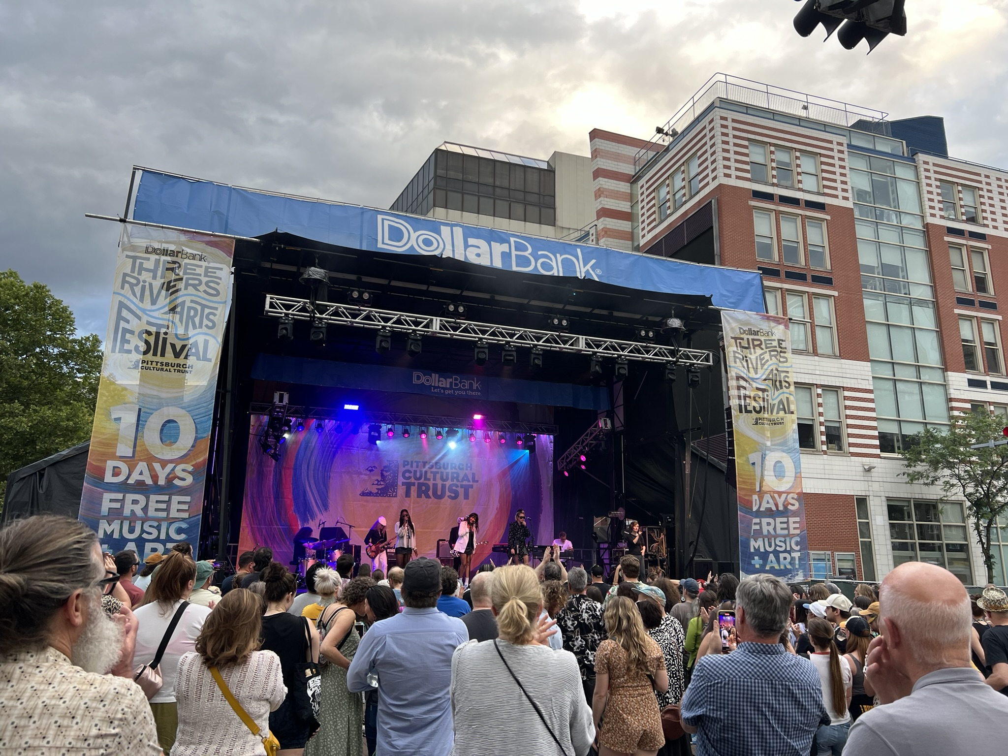 https://npr.brightspotcdn.com/03/7c/c76665d54205bd4103b02e33989c/downtown-pittsburgh-three-rivers-arts-festival-concert-peformance-music-musician-crowd-gathering-summer-activity-program-dollar-bank-stage.JPEG