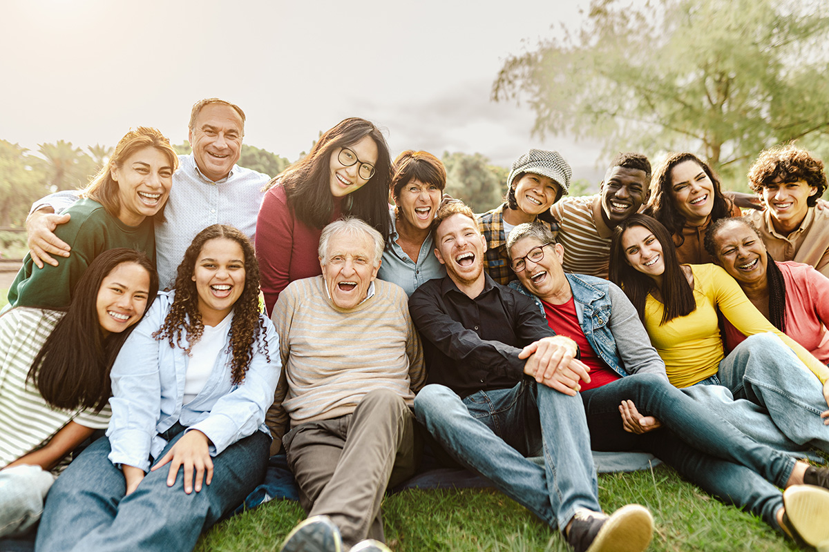 A group of people sitting on the grass laughing.