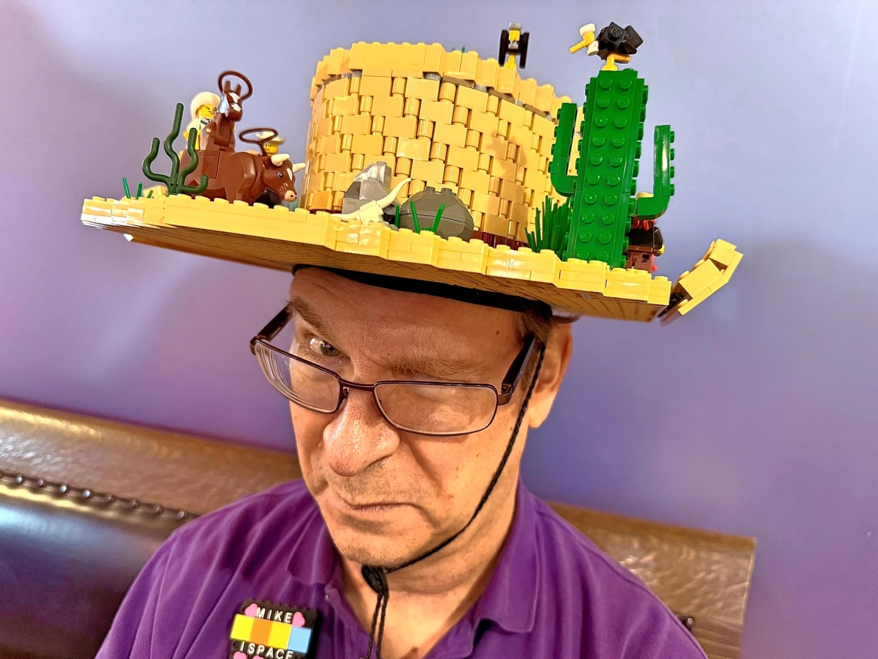 A man wears a LEGO cowboy hat with Lego cowboy scenes on it. 