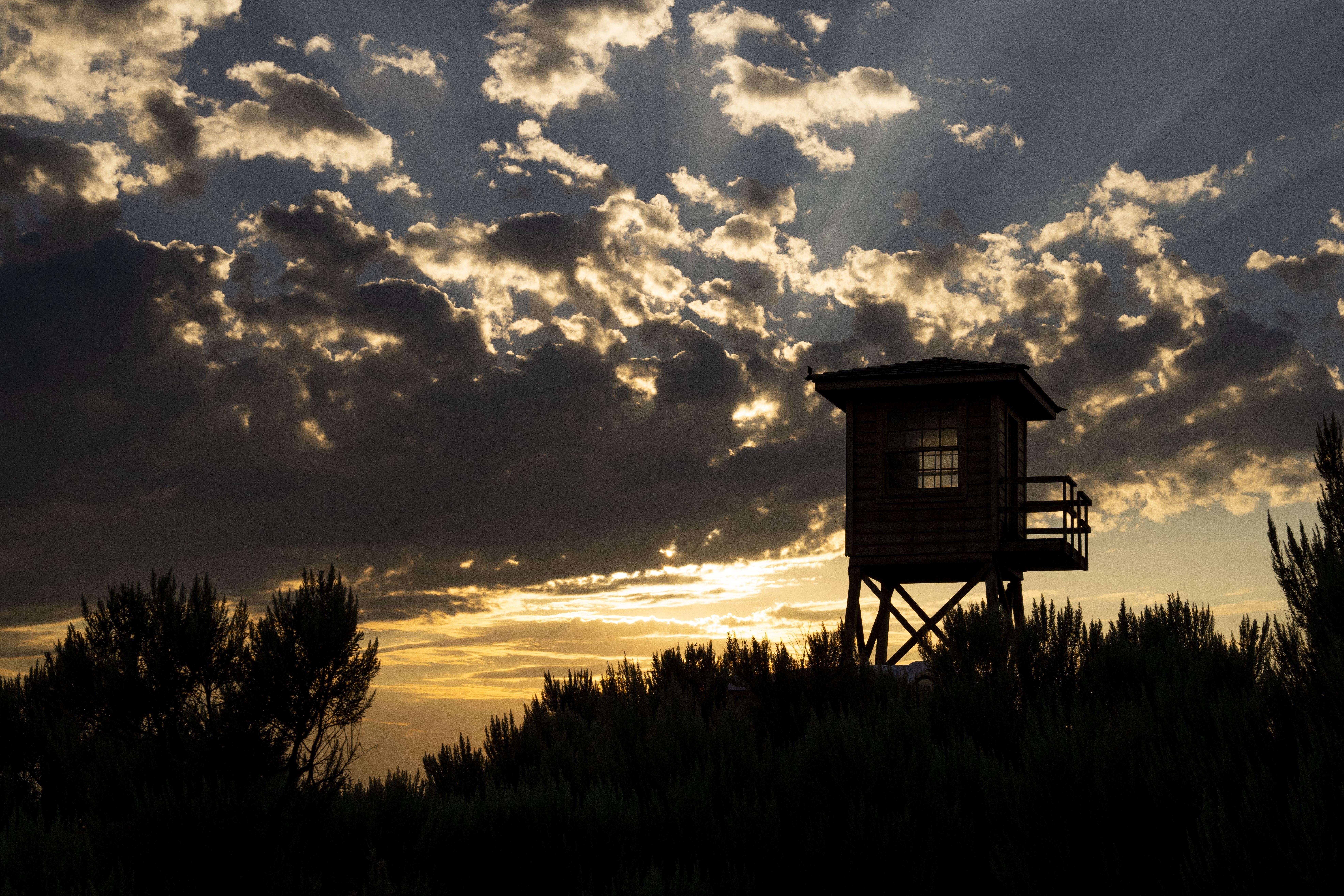 A reconstructed entry guard tower is silhouetted by the sunset at Minidoka National Historic Site, Saturday, July 8, 2023, in Jerome, Idaho.