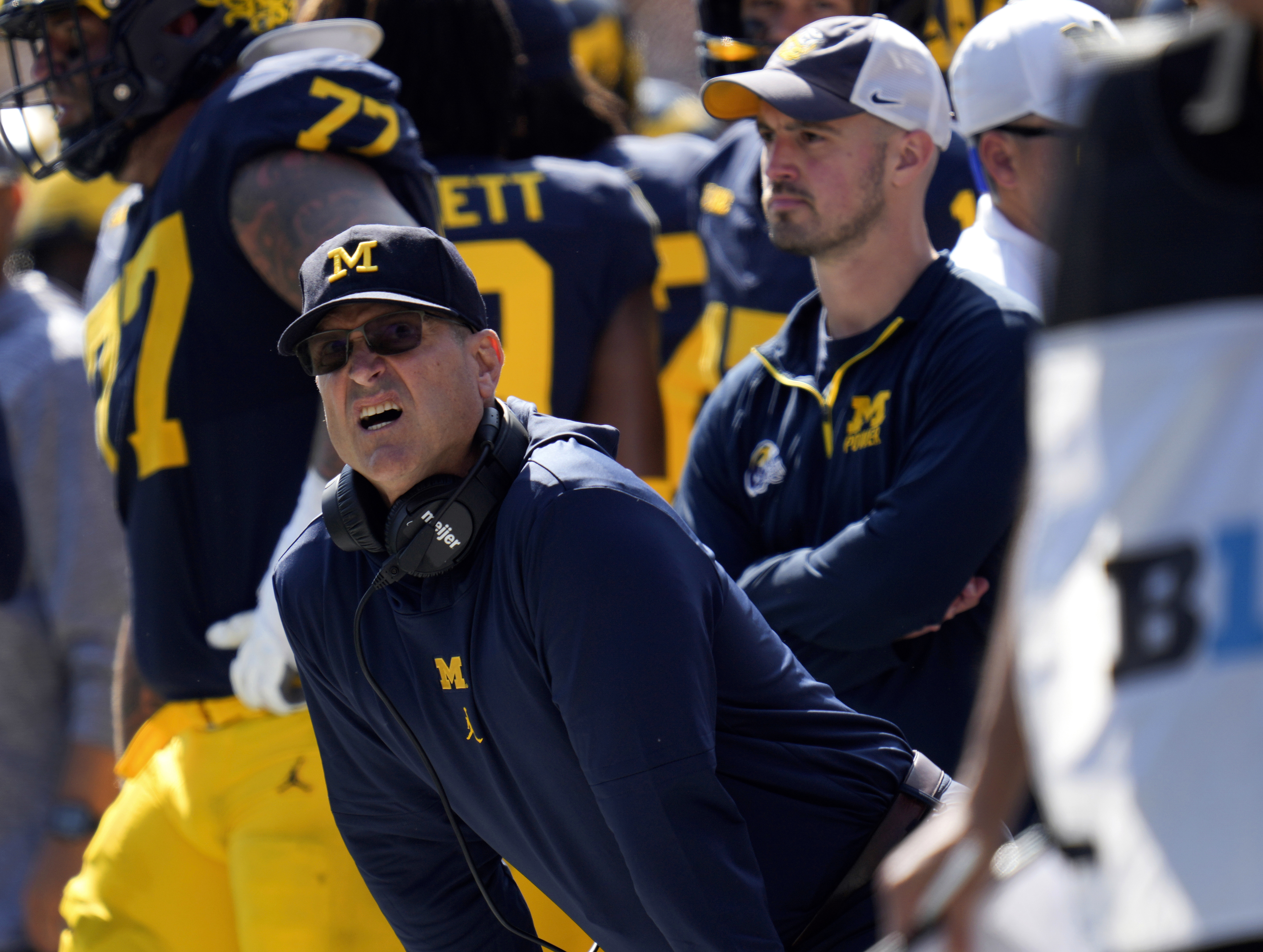 Connor Stalions standing on the Michigan sideline behind Jim Harbaugh during the 2023 season