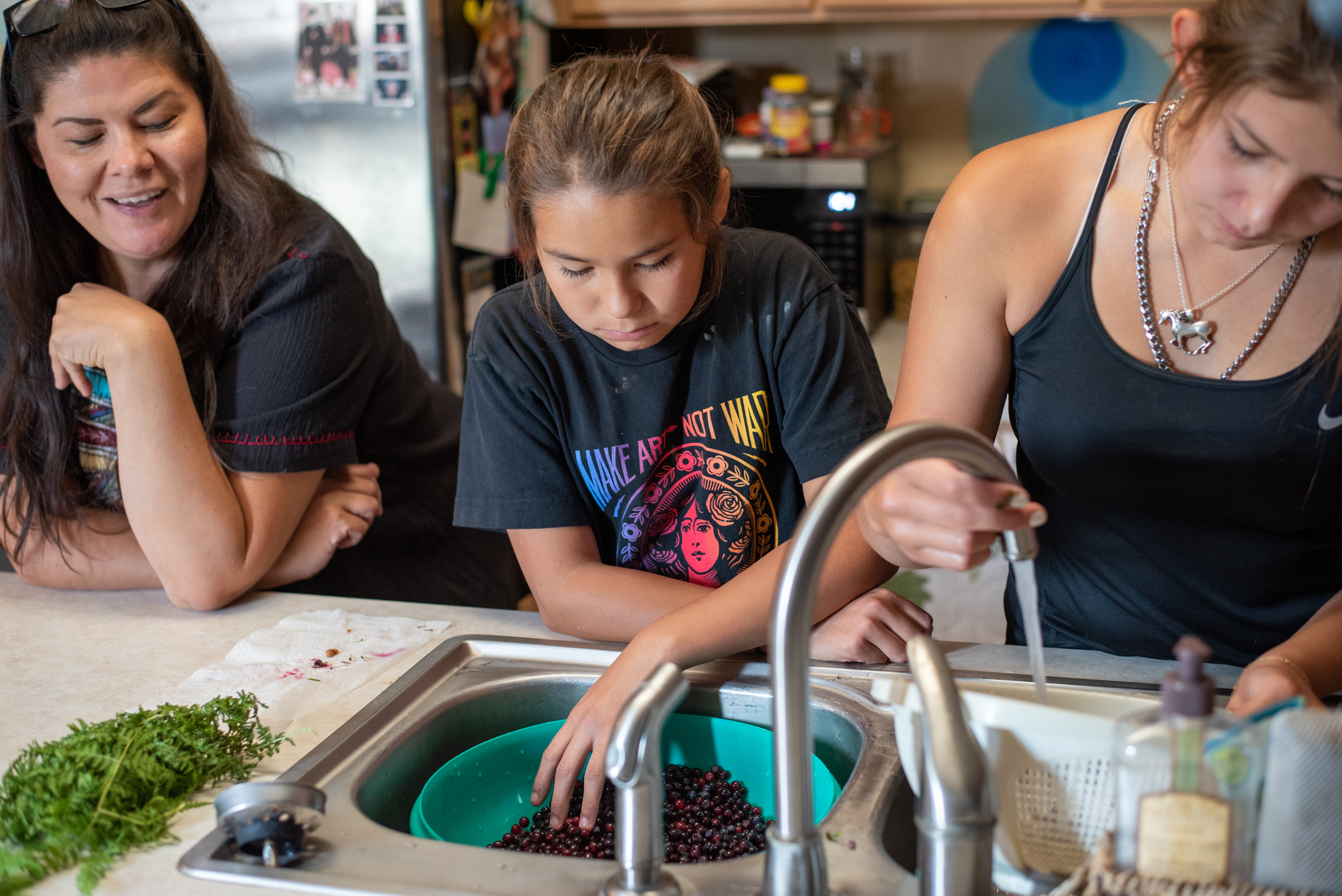 Althea Huesties-Wolf and her daughters Stella, center, and Manaia wash huckleberries and chokecherries in preparation for canning at their home on the Umatilla Indian Reservation in Mission, Oregon. These sacred first foods are considered “sisters” and are eaten at feasts and ceremonies throughout the year.