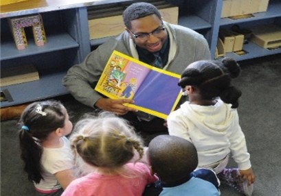 Instructor reading a picture book to a group of young children