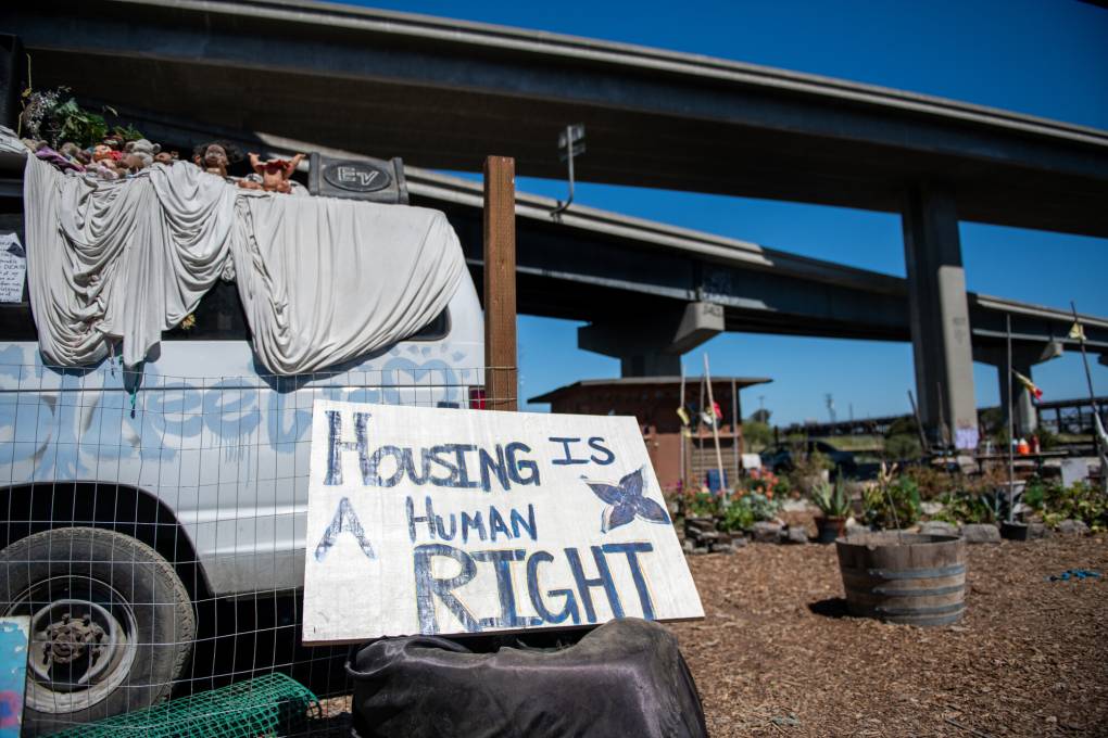 A sign says, ‘Housing is a Human Right’ at the Cob on Wood Project at the Wood Street encampment in West Oakland on Tuesday, July 19, 2022. (Beth LaBerge/KQED)