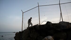 A migrant walks along a rocky shoreline near the border with Morocco after swimming towards Spain's North African enclave of Ceuta on July 31, 2026.