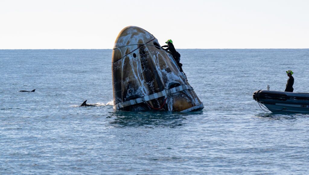 In this handout image provided by NASA, support teams work on the SpaceX Dragon spacecraft shortly after it landed with NASA astronauts Nick Hague, Suni Williams and Butch Wilmore, and Roscosmos cosmonaut Aleksandr Gorbunov onboard on March 18, 2025, off the coast of Florida.