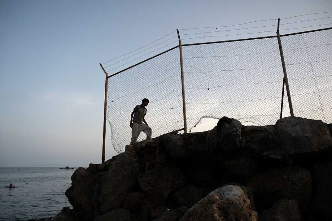 A migrant walks along a rocky shoreline near the border with Morocco after swimming towards Spain's North African enclave of Ceuta on July 31, 2026.