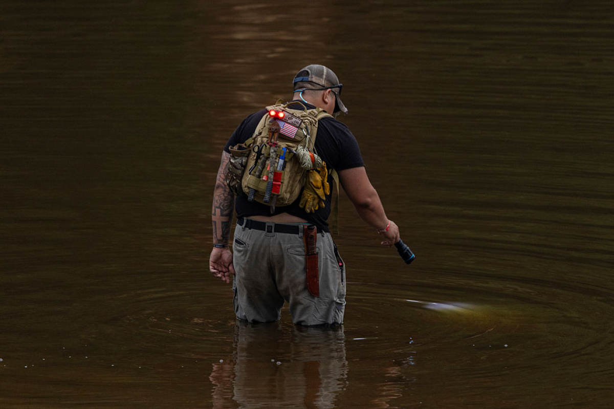 A search and recovery worker shines his flashlight through murky waters on July 6, 2025 in Hunt, Texas, two days after deadly flash floods tore through the area.