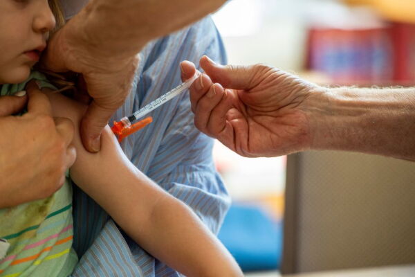 A child receives a vaccination in the arm.