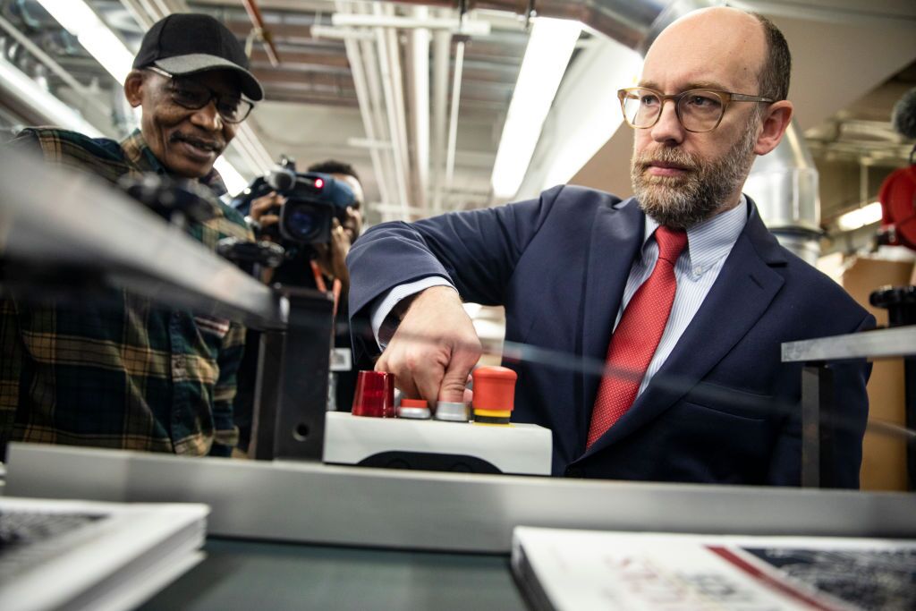 Then-acting Director of the Office of Management and Budget Russ Vought is seen starting the machine that will print copies of then-President Trump