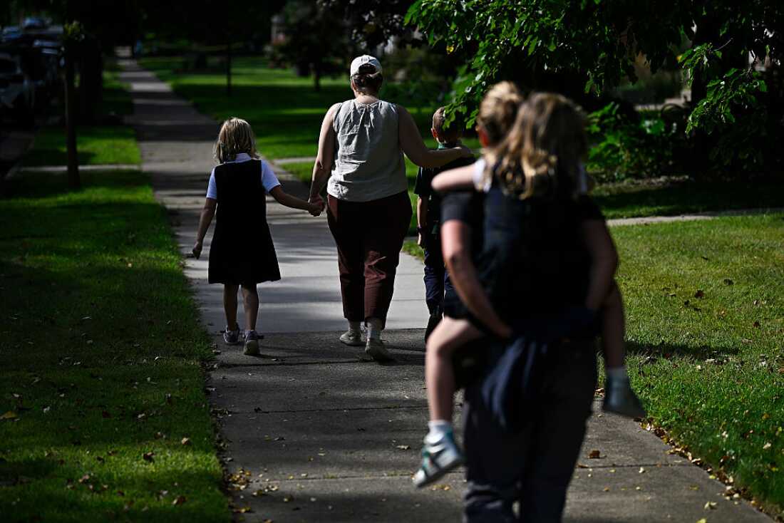 Families depart Annunciation Catholic School in Minneapolis following a mass shooting there on August 27, 2025. Parents are walking down a sidewalk with their children.