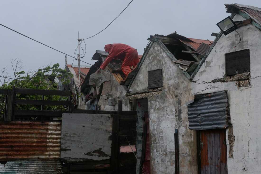 Men remove part of the roof Tuesday in Kingston, Jamaica, as Hurricane Melissa approaches.