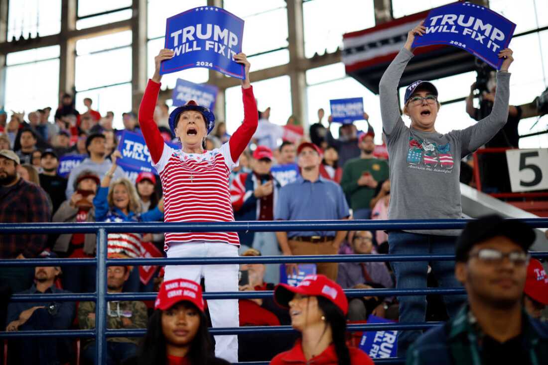 People hold up signs before Republican presidential nominee, former U.S. President Donald Trump holds a campaign rally Nov. 04, 2024 in Raleigh, North Carolina.