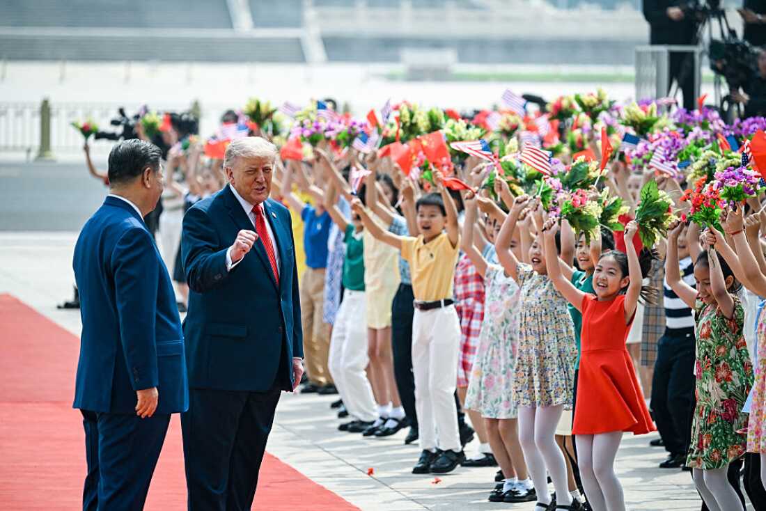 US President Donald Trump (R) and China's President Xi Jinping (L) greet children waving Chinese and US national flags and flowers during a welcome ceremony at the Great Hall of the People in Beijing on May 14, 2026.