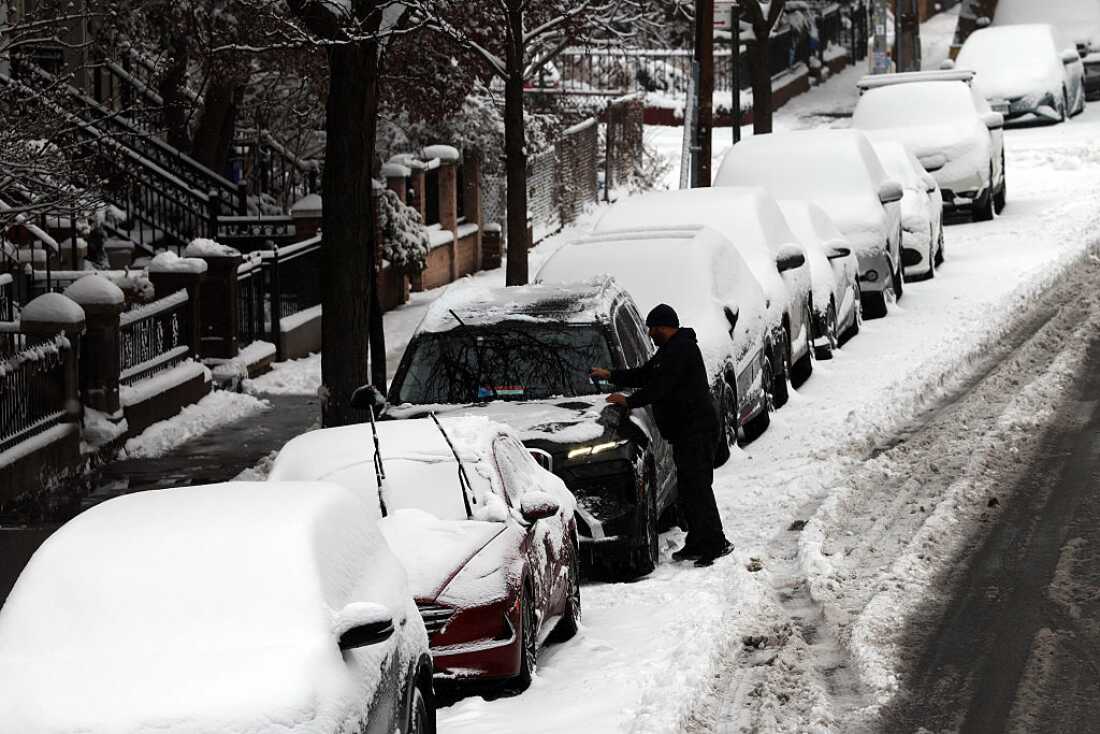 A man cleans off his car of snow in Brooklyn after an overnight storm on Dec. 27, 2025 in New York City.