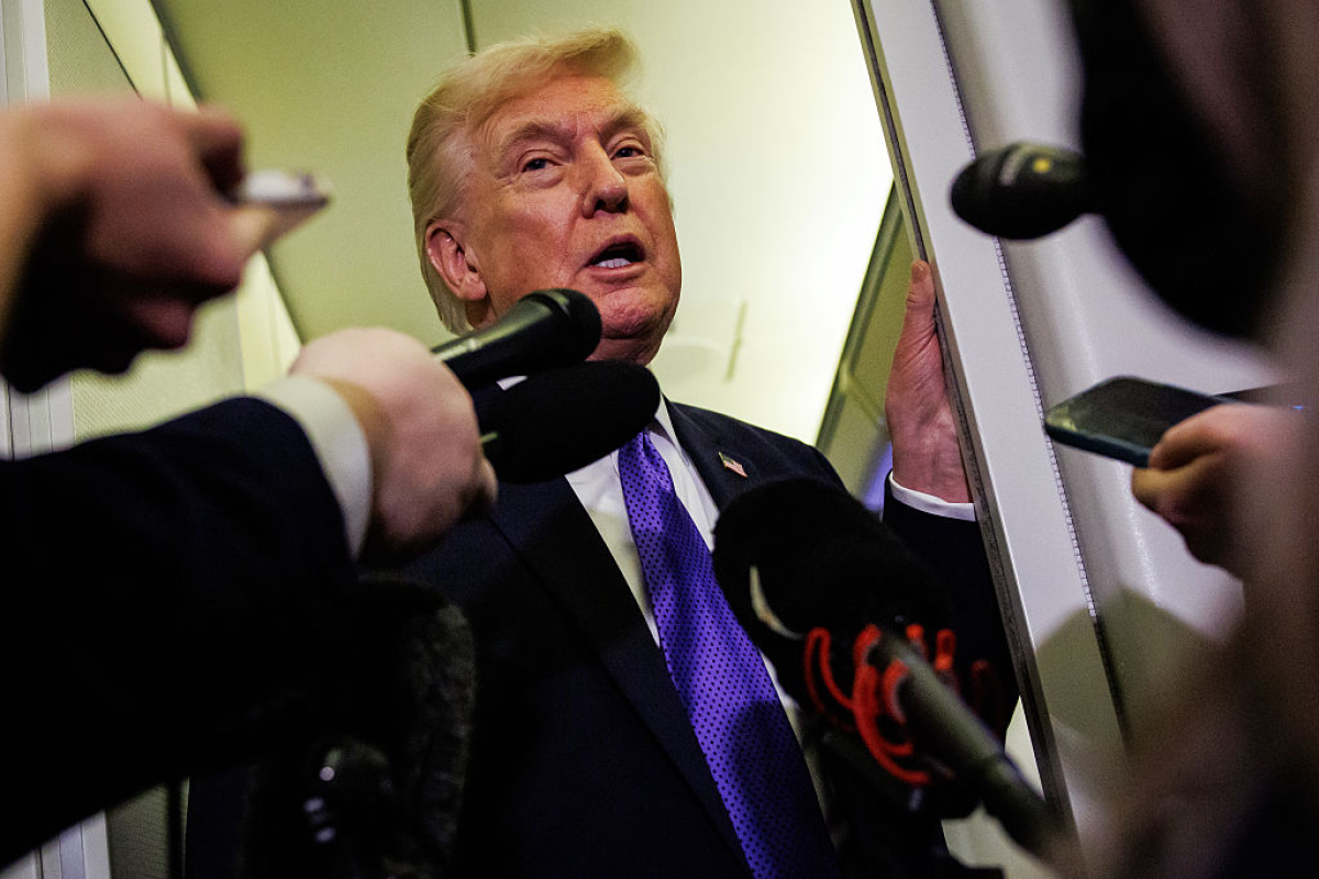 President Trump talks to reporters while aboard Air Force One on Friday en route to Palm Beach, Fla.
