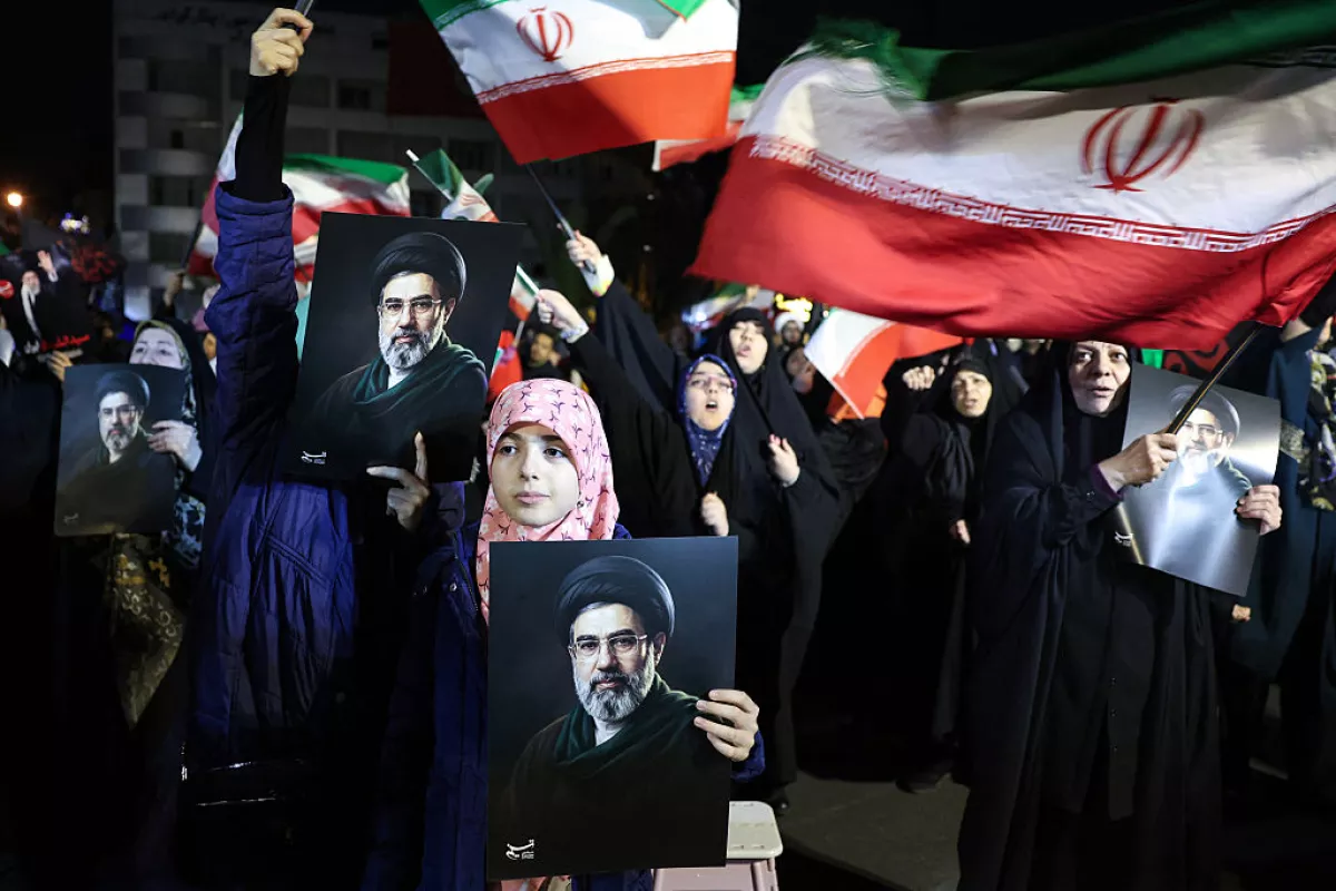 People wave national flags and hold portraits of Iran's supreme leader Mojtaba Khamenei as they march in support of the Iranian armed forces in central Tehran on March 25, 2026.