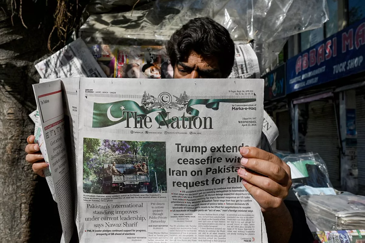 A man reads a newspaper with a front page article referring to anticipated US-Iran peace talks, at a stall in Islamabad on April 22, 2026.