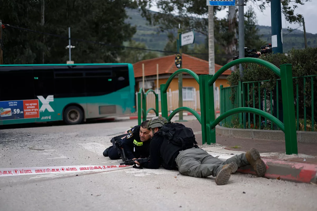 Israeli security forces take cover during a siren alert while gathering at the site of a Hezbollah missile strike that targeted a bus in the northern Israeli border town of Kiryat Shmona on March 23, 2026.