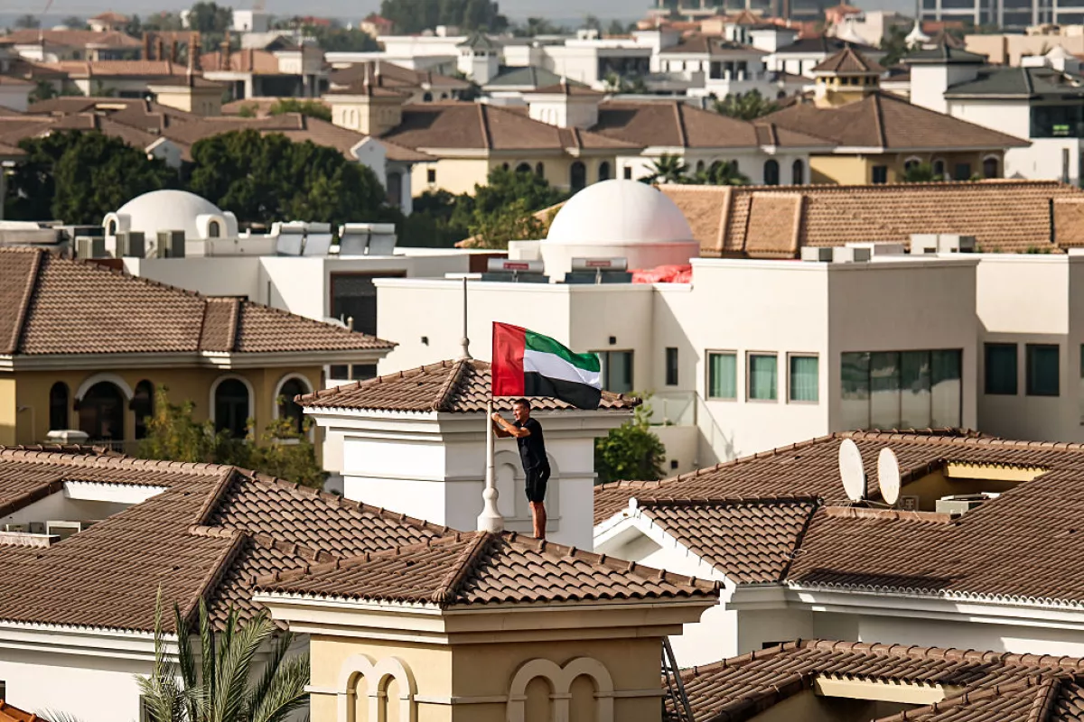 A man fixes the United Arab Emirates' national flag to the roof of his house in Dubai on April 14, 2026, after a call by the UAE' Vice President, Prime Minister and Ruler of Dubai urging people across the country to hoist the flag as a symbol of unity and pride.
