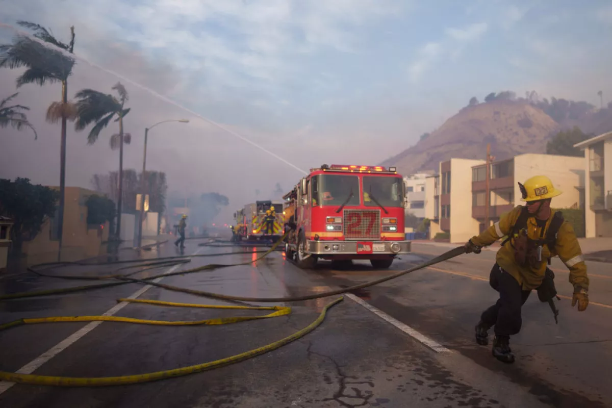 A firefighter drags a hose during the Palisades Fire on Jan. 8, 2025 in Malibu, Calif.