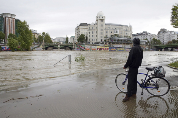 A cyclist looks at Donaukanal channel flood its banks at Urania observatory in central Vienna, Austria, Sunday, Sept. 15, 2024.