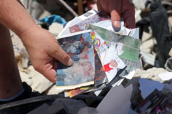 Resident Mohamad Ali Hijazi holds his damaged family photo album amid the rubble of destroyed buildings at a residential area in Tyre on April 23, 2026.