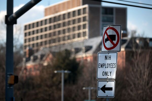 A street sign reads "NIH employees only" and has an arrow pointing traffic to the left.