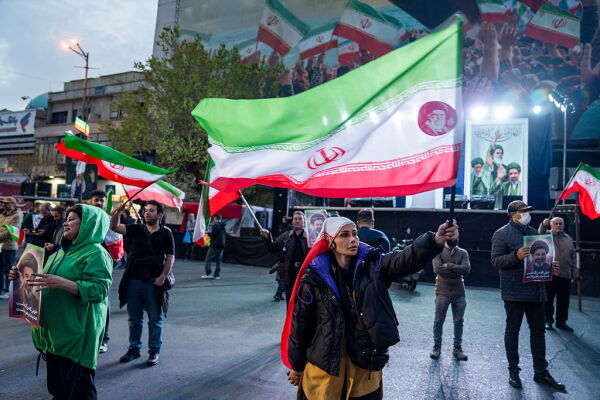 People wave flags as they demonstrate in support of the Iranian government on March 22, 2026 in central Tehran, Iran.