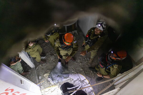 Members of Israel's Home Front Command (HFC) investigate a building damaged by a strike in Tel Aviv on March 28, 2026. On the evening of March 27, the Israeli army reported missiles fired by Iran at Israel.