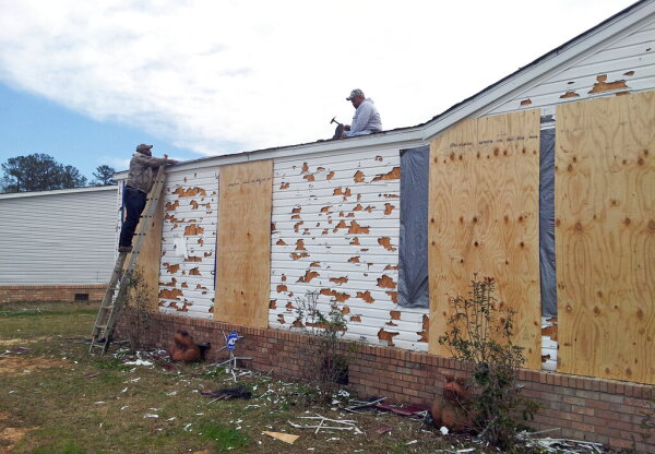 John Purry secures tarps on the roof of his house in Pearl, Miss., Wednesday, March 20, 2013 with the help of his uncle, Amos Wilson, left, covering up damage from Monday's hail storm that hit central Mississippi. Purry believes he is in a race against time as another round of severe weather threatens. Hail broke windows, shattered siding and left holes in his roof.