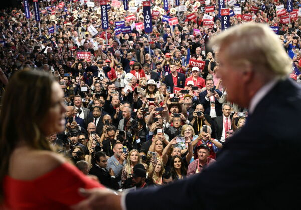 Arkansas Gov. Sarah Huckabee Sanders and former President Donald Trump talk as attendees cheer during the second day of the Republican National Convention in Milwaukee on Tuesday.