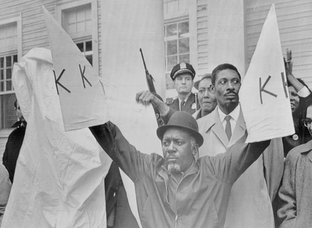 Charles Sims, head of the militant African American civil rights organization, the Deacons for Defense and Justice, displays replicas of Ku Klux Klan robes in defiance of the Klan. During the 1960s, racial tensions flared up in Bogalusa.