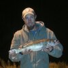 Dustin Kjersem poses for a photo, holding a fish.