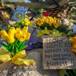 A piece of cardboard reads "Bring Nancy Home!!! Nobody is holding your mothers hostage!!" outside of Nancy Guthrie's home on Feb. 25, 2026 in Catalina Foothills, Ariz.