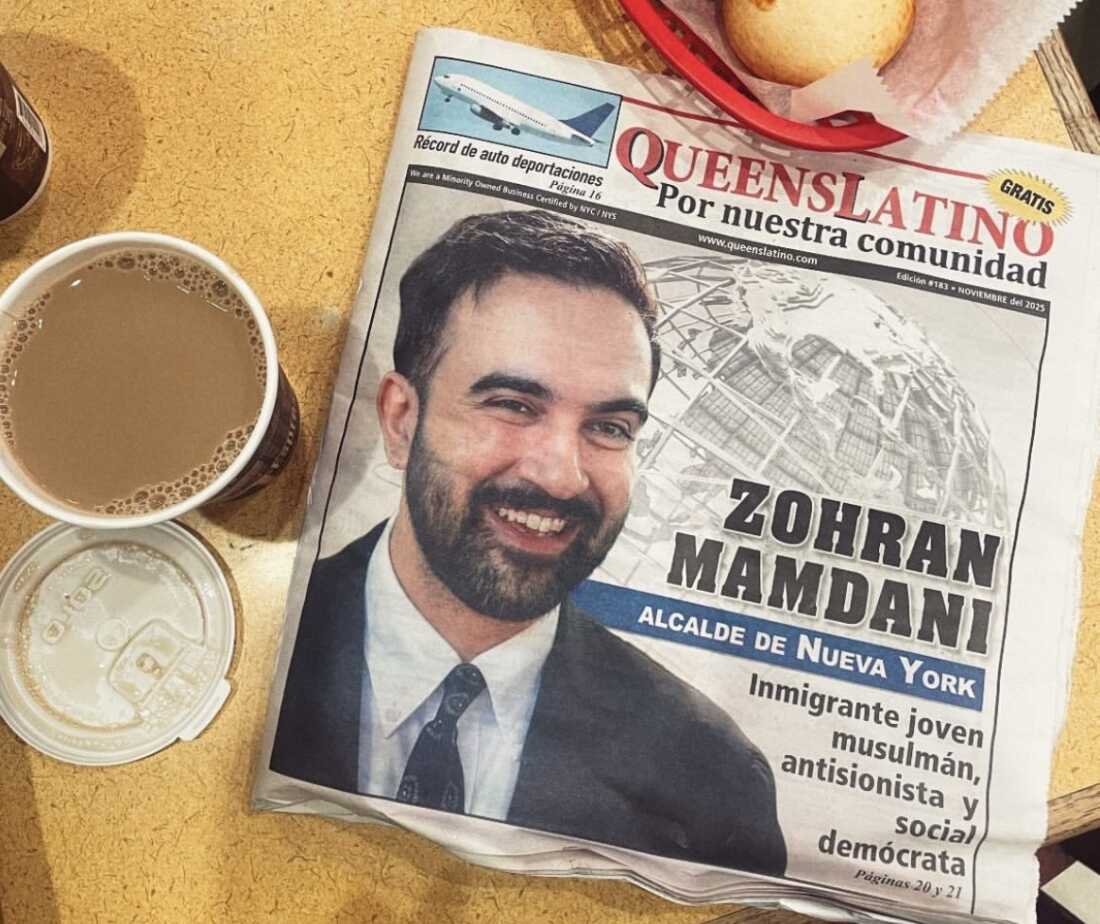 A newspaper in Spanish lies on the table next to a cup of coffee and bread.