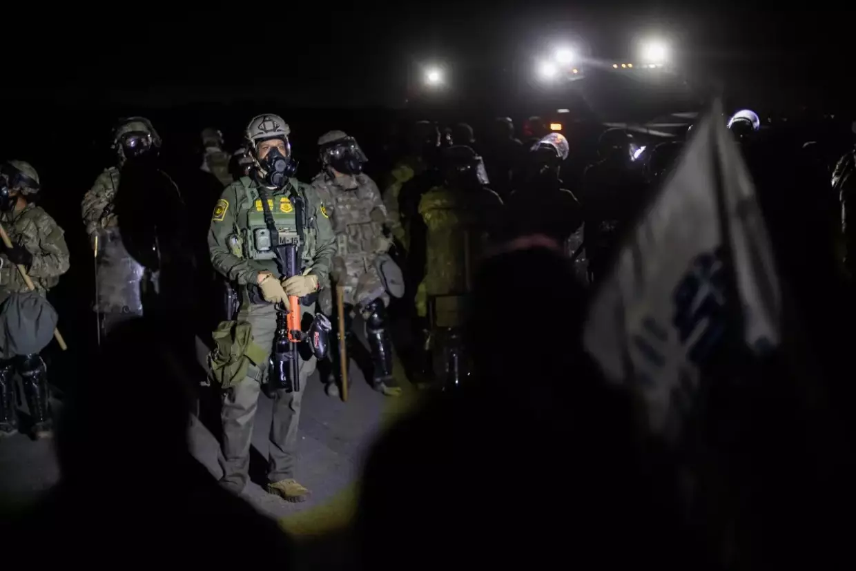 A line of federal immigration agents and protesters stand-off near the Glass House Farms facility outside Camarillo on July 10, 2025. Protesters gathered after federal immigration agents conducted an immigration raid earlier in the day.