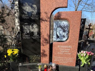 Flowers and candles rest on the headstone for Kuvshynova.