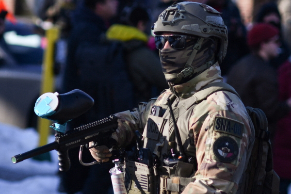 A federal officer stands guard as protestors gather while ICE operates in a residential neighborhood in Minneapolis on Jan. 13, 2026. Hundreds more federal agents were heading to Minneapolis, the US homeland security chief said on January 11, brushing aside demands by the Midwestern city's Democratic leaders to leave after an immigration officer fatally shot a woman protester. In multiple TV interviews, US Homeland Secretary Kristi Noem defended the actions of the officer who shot and killed 37-year-old Renee Nicole Good, whose death has sparked renewed protests nationwide against President Donald Trump's immigration crackdown. (Photo by Octavio JONES / AFP via Getty Images)