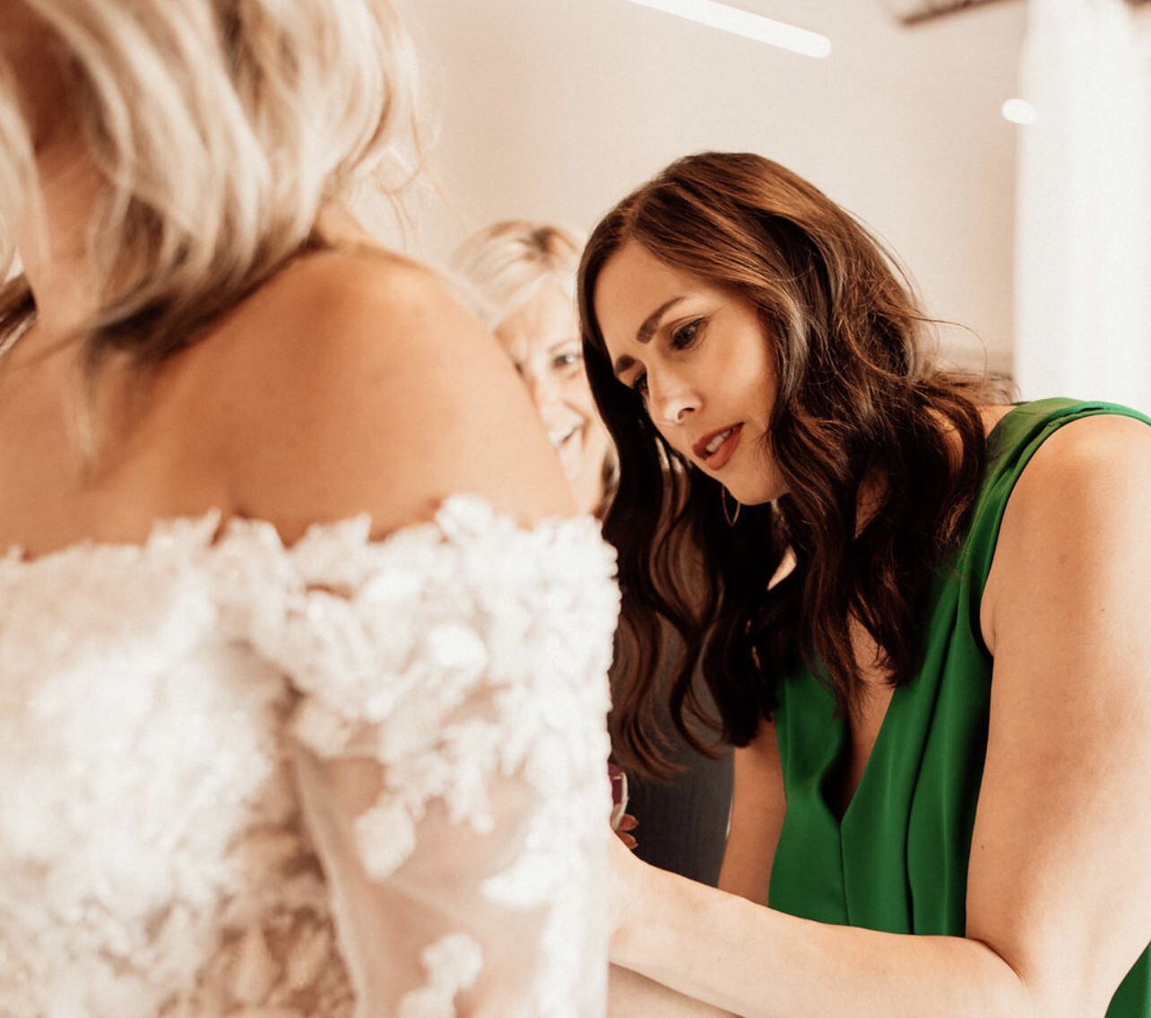 Claire Landgraf helps a bride try on a dress at her shop Finery Bridal Chic in Rochester, Minn.
