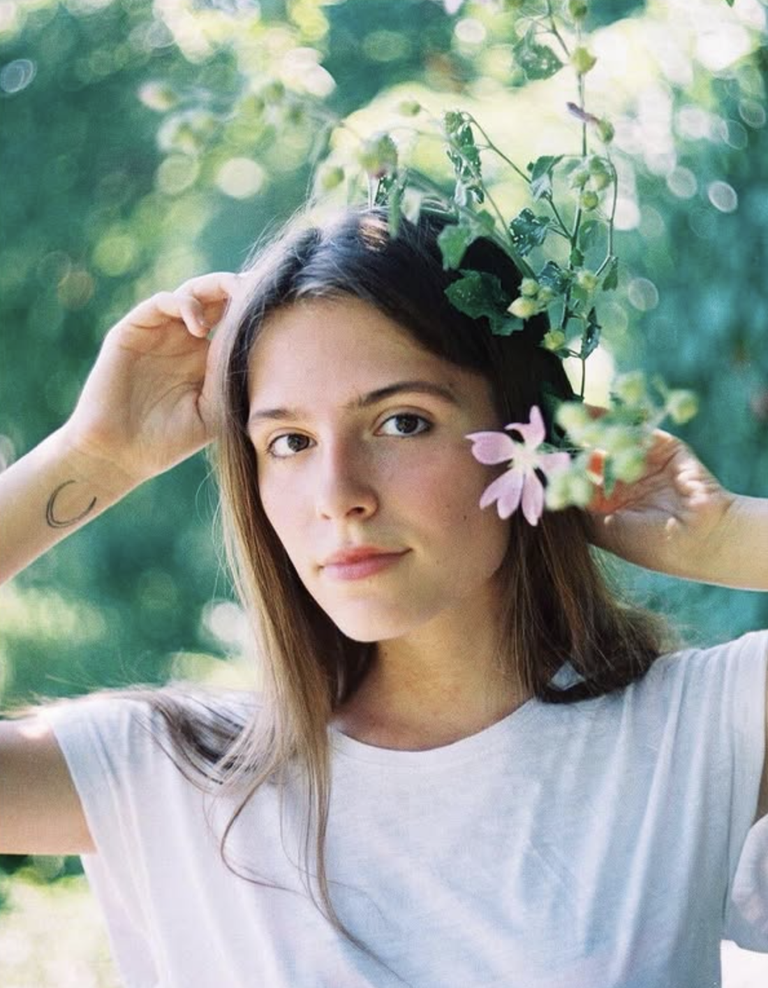 In this 2021 photo of Oleksandra Kuvshynova, she is holding a flower near her face and wearing a white shirt.