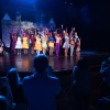 Students gather onstage in front of a castle facade. The audience is standing. 