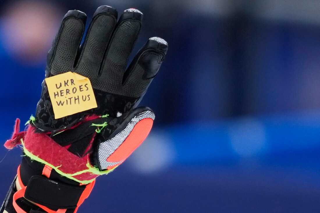 Ukraine's Dmytro Shepiuk holds a sticker reading "UKR heroes with us" at the finish area during a men's super-G race, at the 2026 Winter Olympics, in Bormio, Italy, Wednesday.
