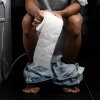 Young man holding paper toilet seat at home.