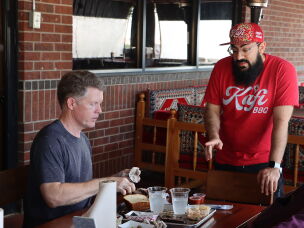 Kafi BBQ owner Salahodeen Abdul-Kafi (center) speaks with customer Jonathan Tate in Irving, Texas.