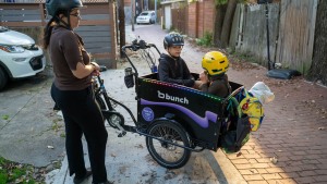 Lelac Almagor waits as her kids get ready for the ride to school. Her cargo bike is technically a trike, with two wheels in front for more stability.